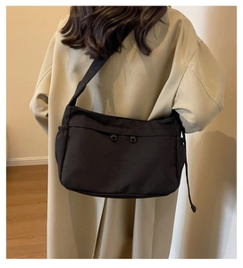 Détail du grand sac bandoulière noir en toile avec doubles fermetures éclair et cordons latéraux
