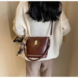 Détail d'un sac seau vintage marron foncé avec fermoir doré et breloque lapin en peluche