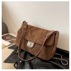 Detail of brown suede quilted bag featuring a silver twist lock and metal chain strap
