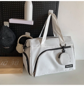 Details einer großen weißen Reisetasche mit passender Minitasche und Logo-Aufnäher