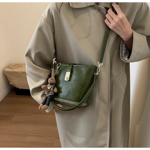 Détails du sac seau vintage vert foncé avec fermoir doré et breloque lapin sur modèle