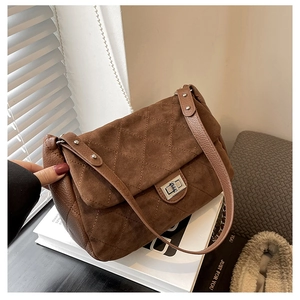 Detailed view of dark brown quilted shoulder bag with silver twist lock and suede texture