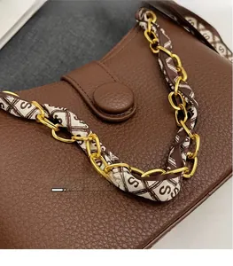 Detail of brown litchi pattern leather bag with gold chain and silk scarf strap
