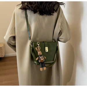Détail du sac seau en cuir vert foncé avec fermeture éclair et pendentif lapin