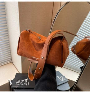 Dettaglio borsa a bauletto in pelle scamosciata marrone con cerniera e tracolla regolabile