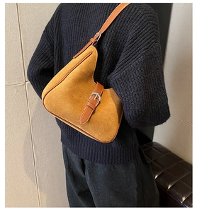 Dettaglio borsa a tracolla marrone opaco con design asimmetrico su un maglione nero a maglia