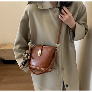 Gros plan du sac seau vintage marron avec fermoir tournant doré et breloque lapin