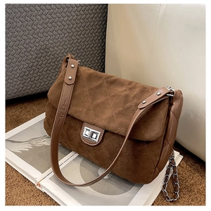 Detail of quilted suede shoulder bag featuring a silver twist lock and leather chain strap