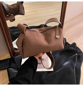 Vista dettagliata della borsa a cuscino in camoscio marrone con tracolla larga e zip