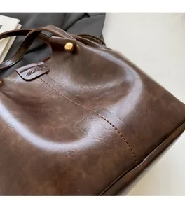 Detail of dark brown vintage leather bucket bag with gold ball hardware and fine stitching