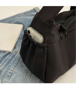 Détail de la poche latérale d'un sac cabas noir contenant un smartphone avec coque d'ours