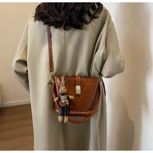 Détail du sac seau vintage marron avec fermoir métallique et breloque lapin mignonne