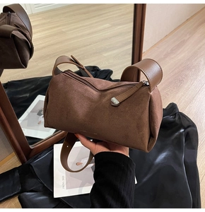 Dettaglio della borsa a cuscino in camoscio marrone con tracolla in pelle e cerniera