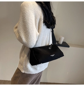 Dettaglio macro della borsa in pelle nera opaca con borchie argentate e logo alla moda