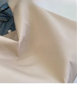 Detailed close-up showing the smooth satin texture of the cream Oxford fabric bag