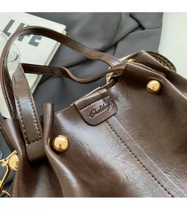 Close-up of deep brown leather bag showing golden rivets and precise stitching details