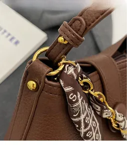 Detail of brown litchi leather bag with gold buckle and silk scarf wrapped handle