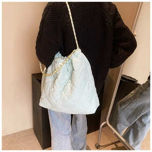 Gros plan sur le sac seau matelassé bleu clair avec chaîne dorée et bandoulière en cuir