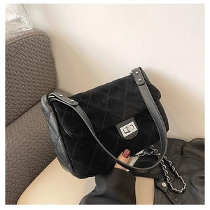 Detail of black quilted suede bag with silver turn-lock and leather chain strap