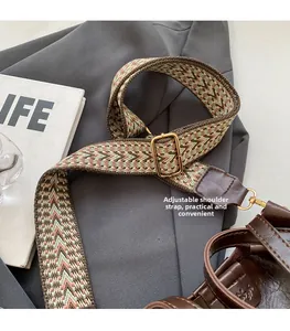 Close-up of adjustable woven shoulder strap with retro pattern and gold metal buckle