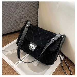 Detail of matte quilted crossbody bag with silver twist lock on a textured surface
