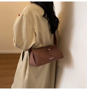 Dettaglio della borsa a cuscino marrone opaca con scritte moda e rivetti in metallo