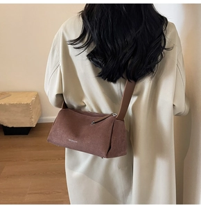 Borsa a tracolla in pelle scamosciata marrone opaca con ampia tracolla indossata da modella