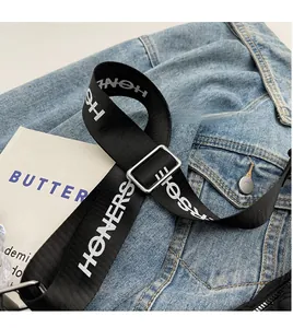 Dettaglio della tracolla regolabile in nylon nero con scritta HONERS bianca e fibbia in metallo