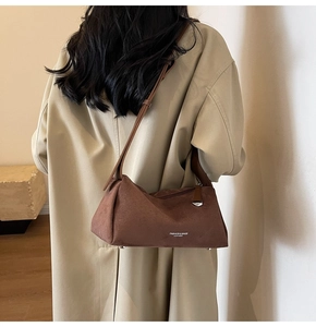 Dettaglio della borsa in pelle opaca testa di moro con tracolla su cappotto beige