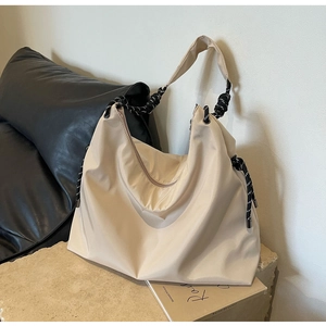 Close-up of beige Oxford tote bag featuring contrast woven rope shoulder strap detail