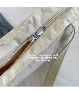 Detail of smooth silver metal zipper head on a beige nylon tote with yellow lining