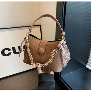 Detail of brown lychee grain leather handbag with silk scarf wrapped chain strap