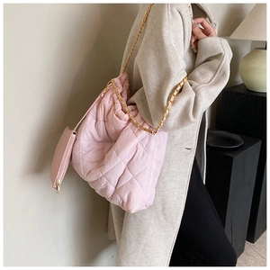 Détail d'un sac seau en nylon matelassé rose avec chaîne dorée et accessoire petite pochette