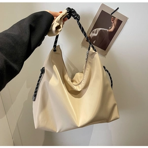 Detail of beige nylon tote bag featuring stylish black and white braided rope handle