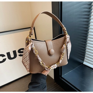 Detailed macro view of brown lychee grain leather handbag with silk scarf and chain