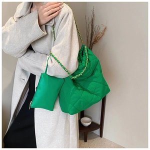 Détail du sac seau matelassé en nylon vert vif avec une bandoulière en chaîne dorée