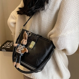 Sac seau en cuir noir chic avec breloque lapin porté sur un pull en maille blanc