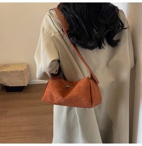 Dettaglio della borsa in pelle scamosciata color caramello con borchie metalliche