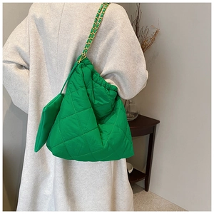 Détail du sac seau matelassé en nylon vert avec chaîne dorée et petite pochette
