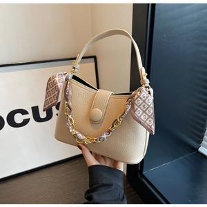 Detail of cream leather hobo bag with a decorative silk scarf and gold chain handle