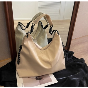 Detail of beige crescent oxford tote with braided rope knot and wide shoulder strap