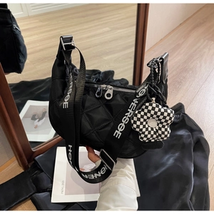Détail du sac hobo en nylon matelassé noir avec large bandoulière et pendentif fleur damier