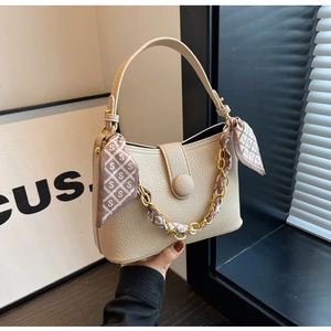 Detail of beige faux leather handbag with gold chain and patterned silk scarf wrap