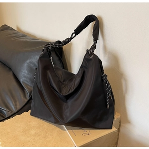 Detail of black nylon tote bag featuring woven rope strap and silver hardware accents