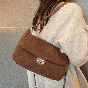 Quilted brown suede crossbody bag with metal chain strap and turn-lock closure