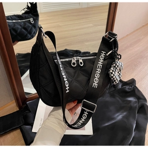 Détail du sac hobo noir matelassé avec double fermeture éclair et charm floral