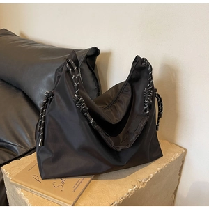 Detailed view of black nylon tote bag featuring stylish black and white braided rope straps