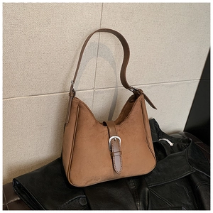 Dettaglio della texture scamosciata marrone opaca e fibbia in metallo su borsa hobo