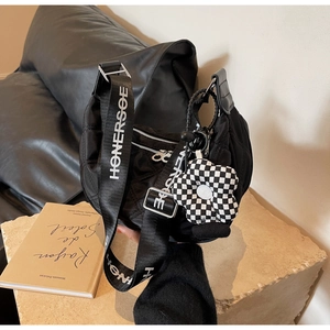 Détail du sac en nylon matelassé noir avec bandoulière large et breloque fleurie