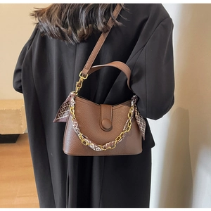 Crossbody view of brown leather bag with golden chain and silk scarf detail